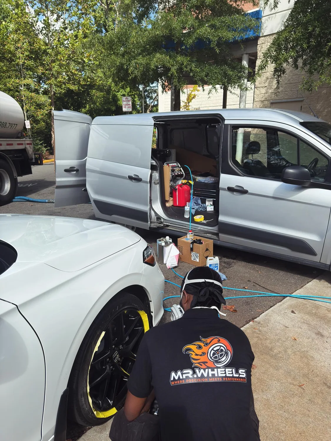 MR.WHEELS technician working beside a customer vehicle and mobile service van